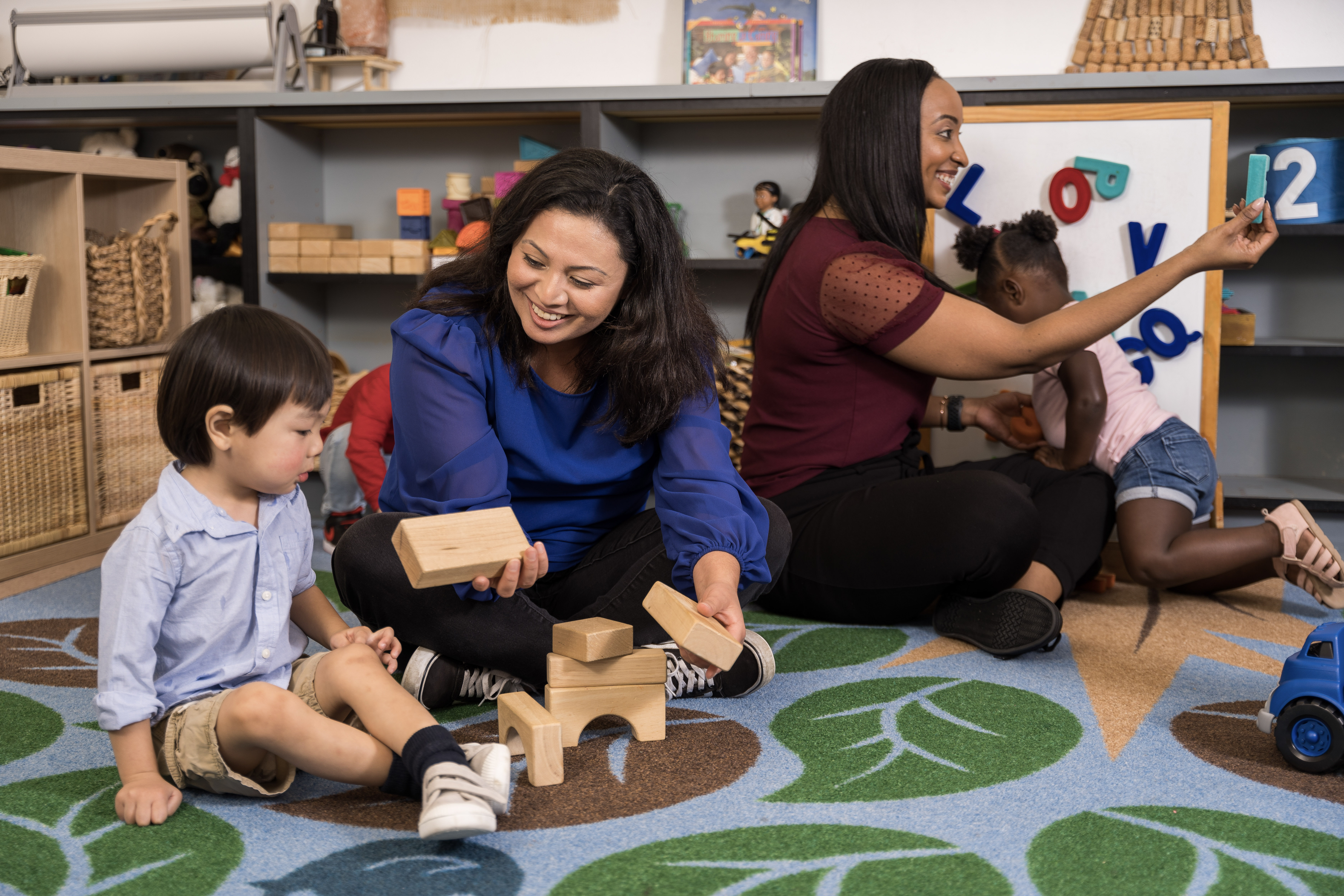 Teachers and children playing with wooden blocks